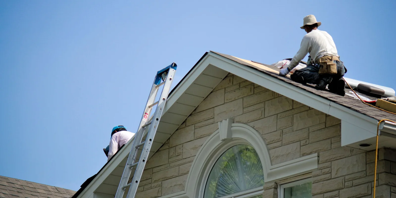 Trabajadores reparando la cubierta de una vivienda bajo cielo despejado